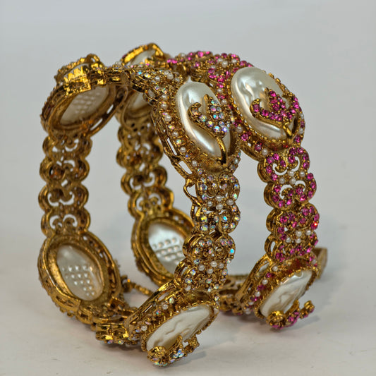Gold bracelet with pearls and pink stones on a white background