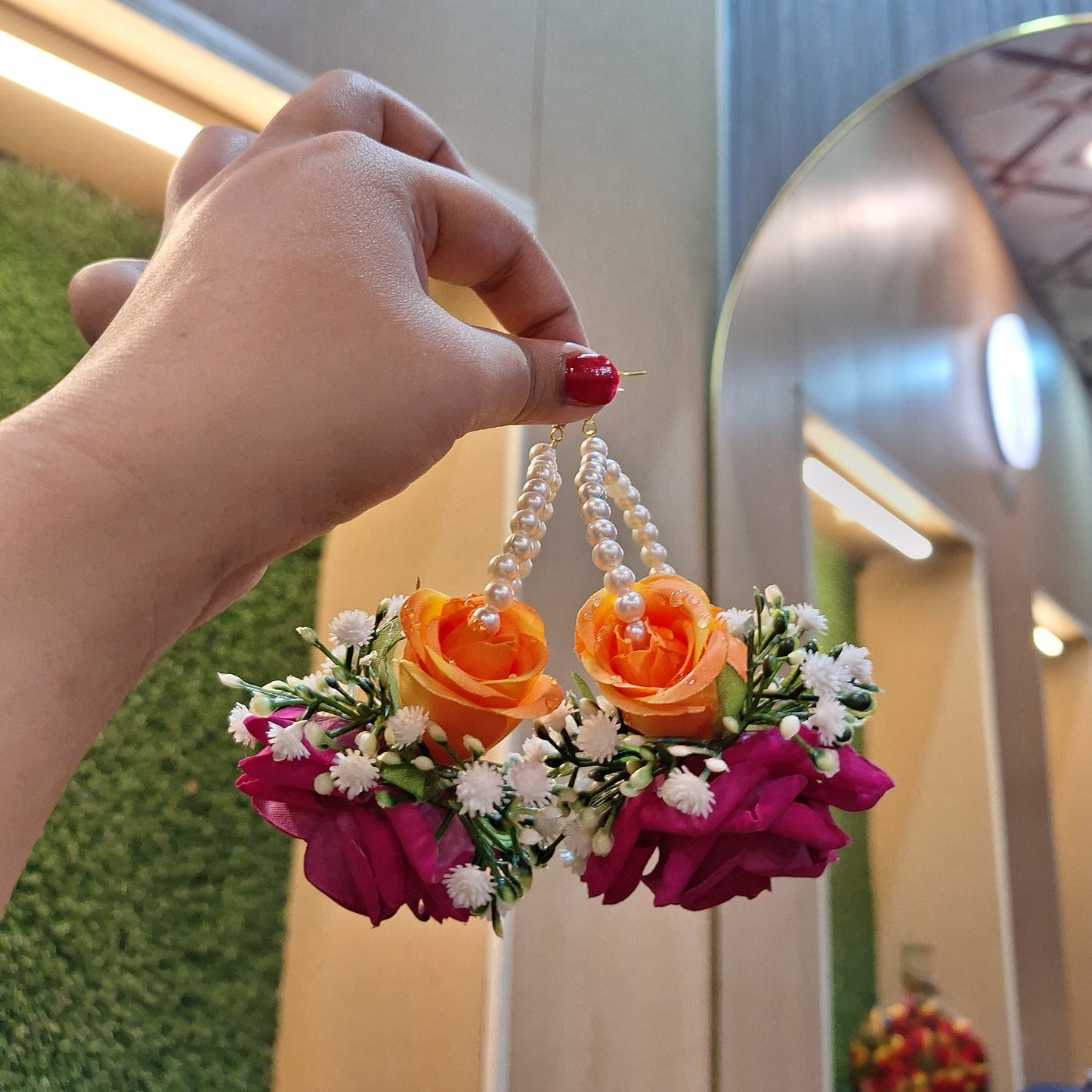 Bright pink and orange floral earrings featuring velvet and silk roses, white baby’s breath, greenery, and elegant pearl detailing.