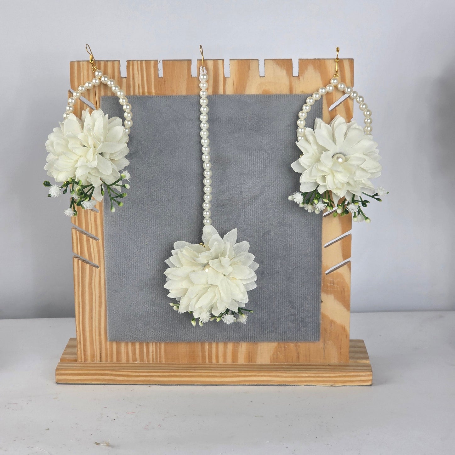 Set of white floral hair accessories on a gray board with wooden frame against a light gray background