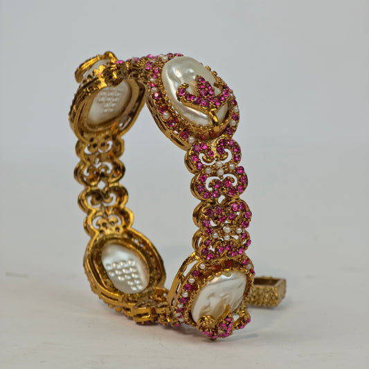 Gold bracelet with pink gemstones on a white background