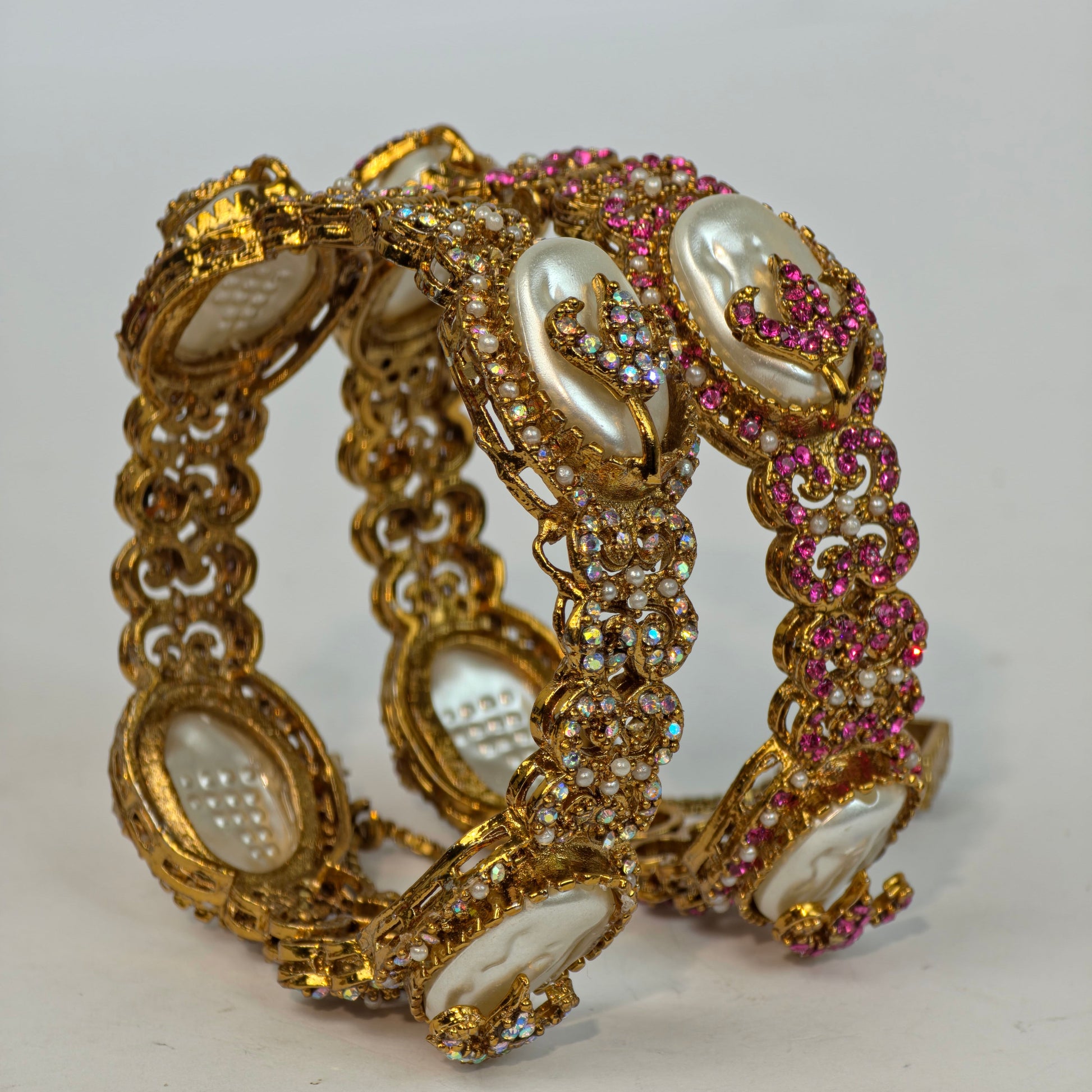 Gold bracelet with pearls and pink stones on a white background
