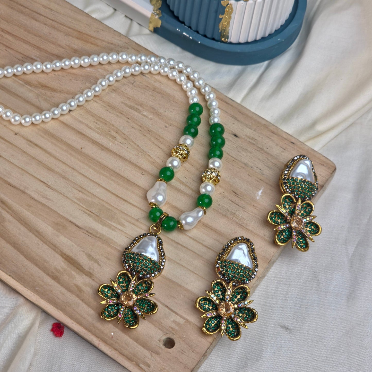 Jewelry set with floral earrings and a necklace on a wooden board.