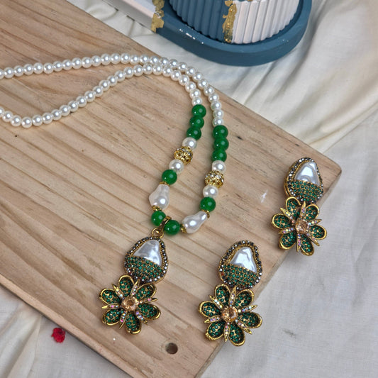 Jewelry set with floral earrings and a necklace on a wooden board.