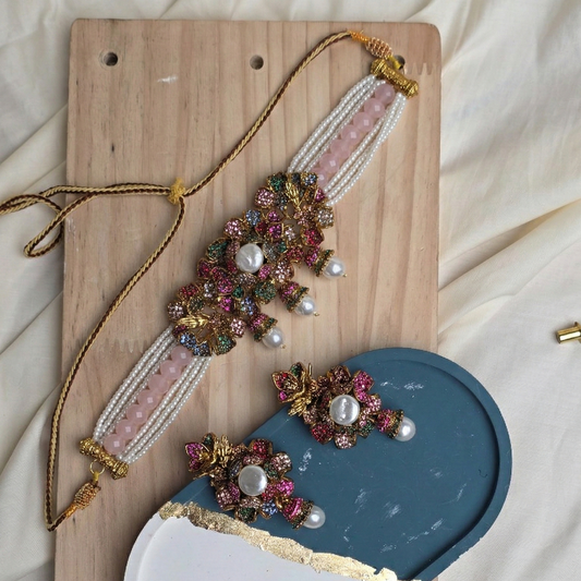 Decorative jewelry piece with beads and pearls on a wooden board.