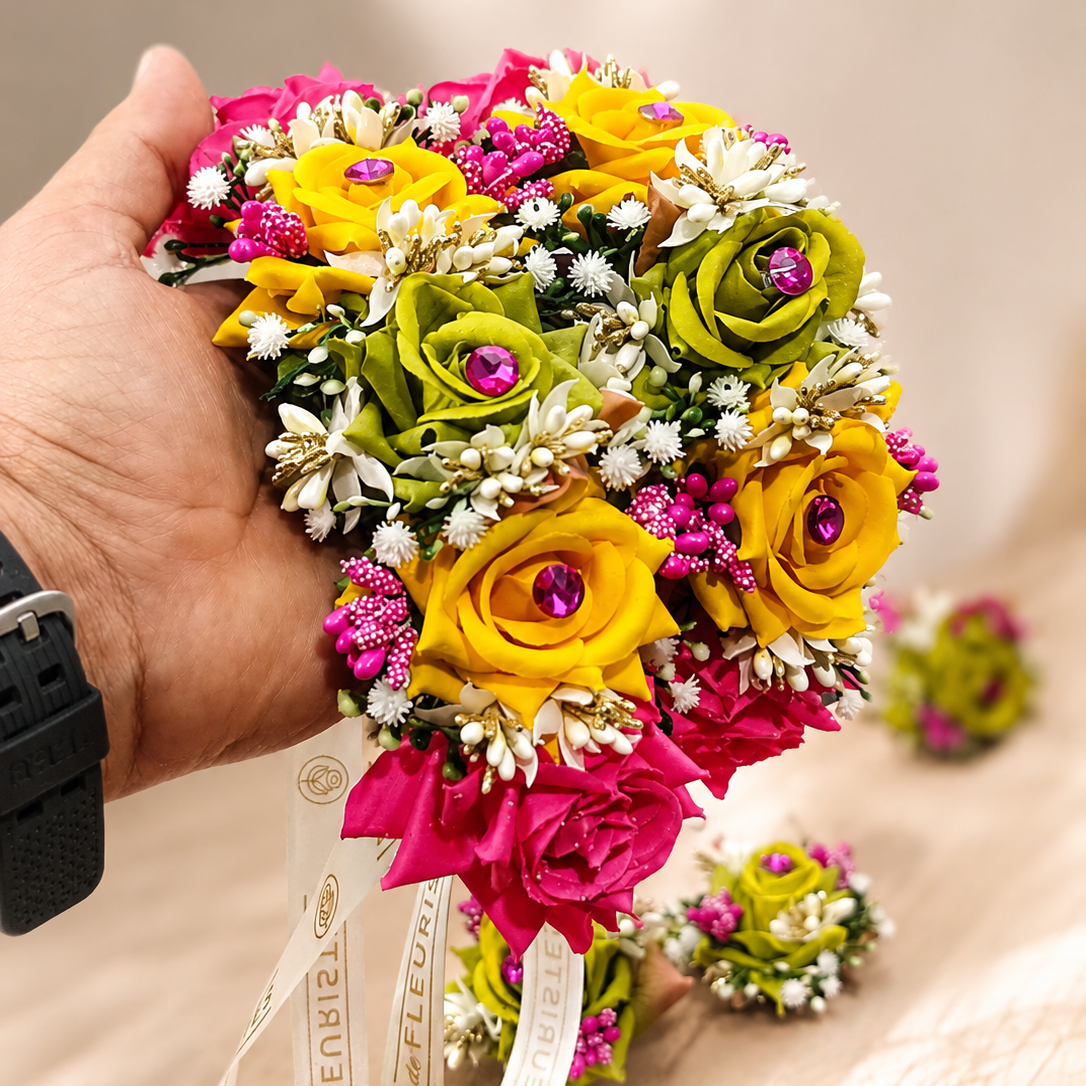 Complete De Fleuristes Mehndi floral jewellery set featuring green, yellow and pink roses, pearl earrings, matching hand gajras and bridal bouquet.