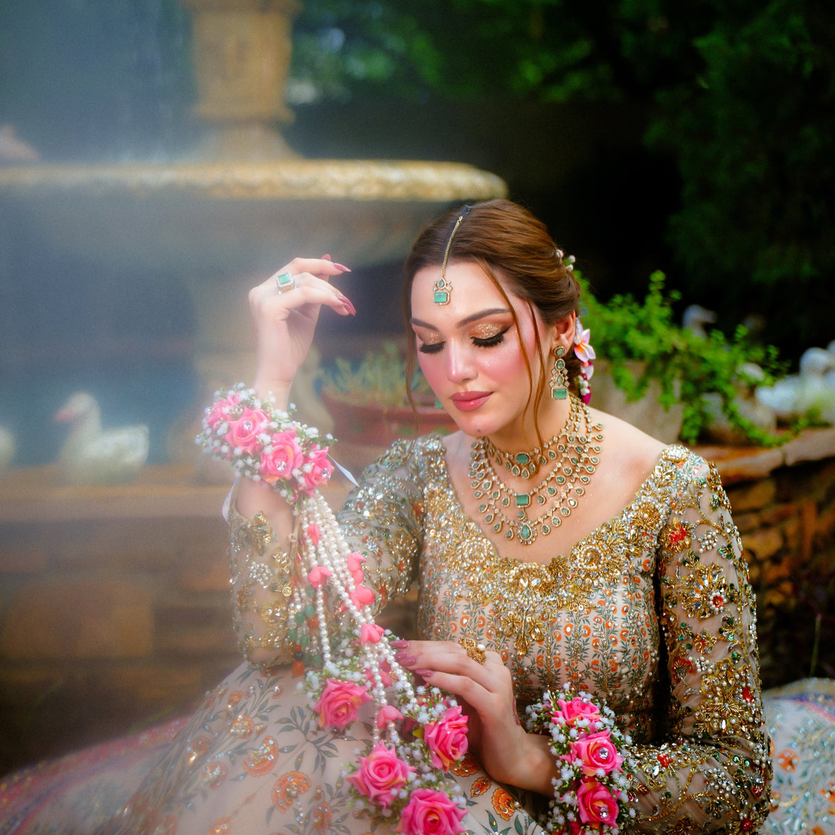 Close-up of a pink floral wrist gajra designed with layered rose flowers, delicate white fillers and long pearl drops, creating a fuller statement hand accessory for Pakistani brides.
