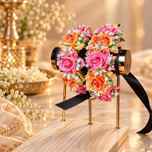 Colourful bridal floral gajra pair created with layered pink and orange artificial roses, tiny white flowers, greenery and sparkling centre accents for a festive Mehndi, Mayon or Dholki look.