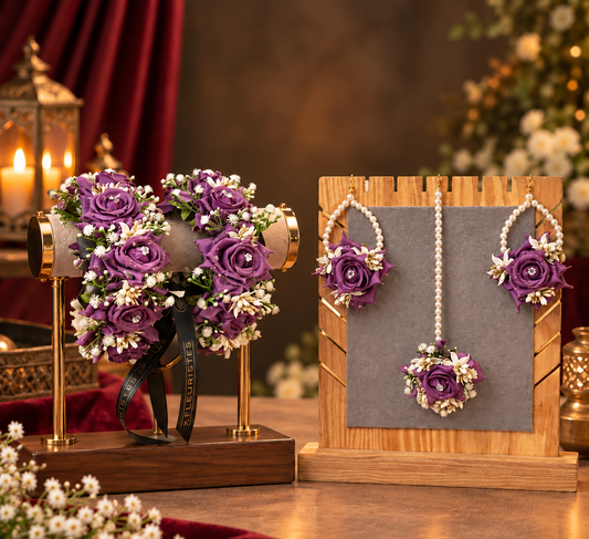 Purple rose floral accessories displayed on stands, including a wristlet with a matching floral brooch and a matching floral necklace with pearl-like beads, set against a warm, decorated background.